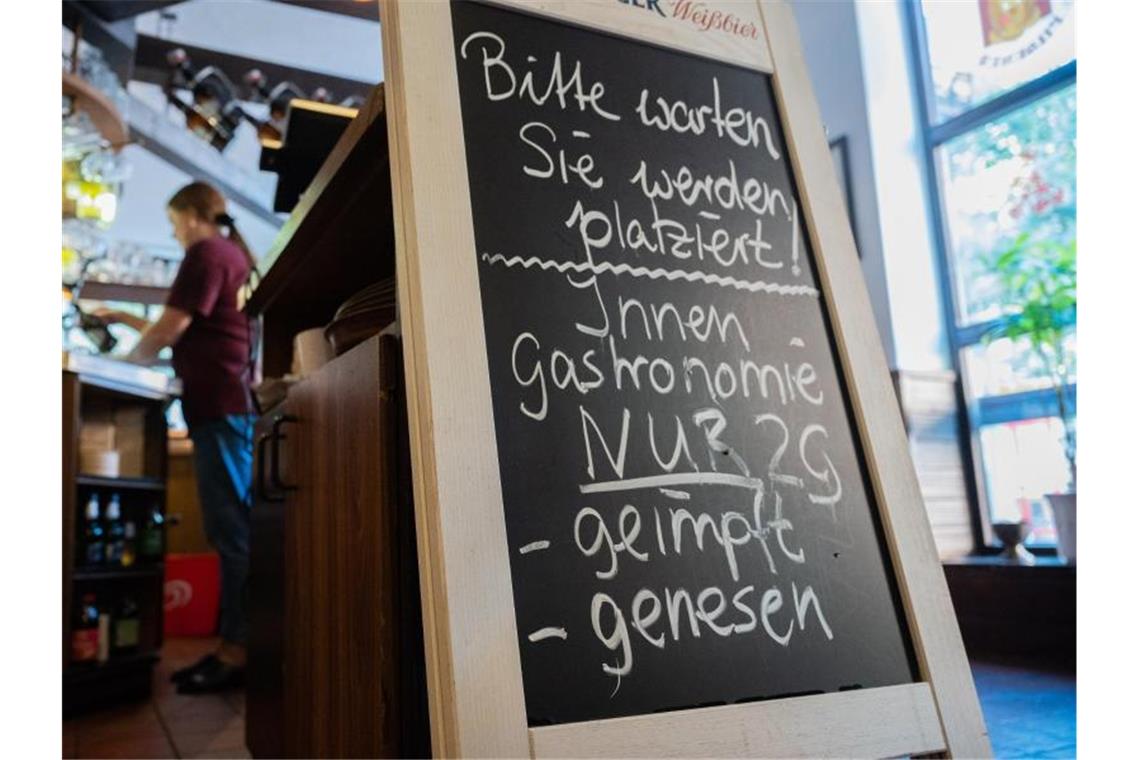 Eine Tafel mit der Aufschrift „Innengastronomie - Nur 2G - geimpft - genesen“ steht in Schadt’s Brauerei Gasthaus. Foto: Julian Stratenschulte/dpa