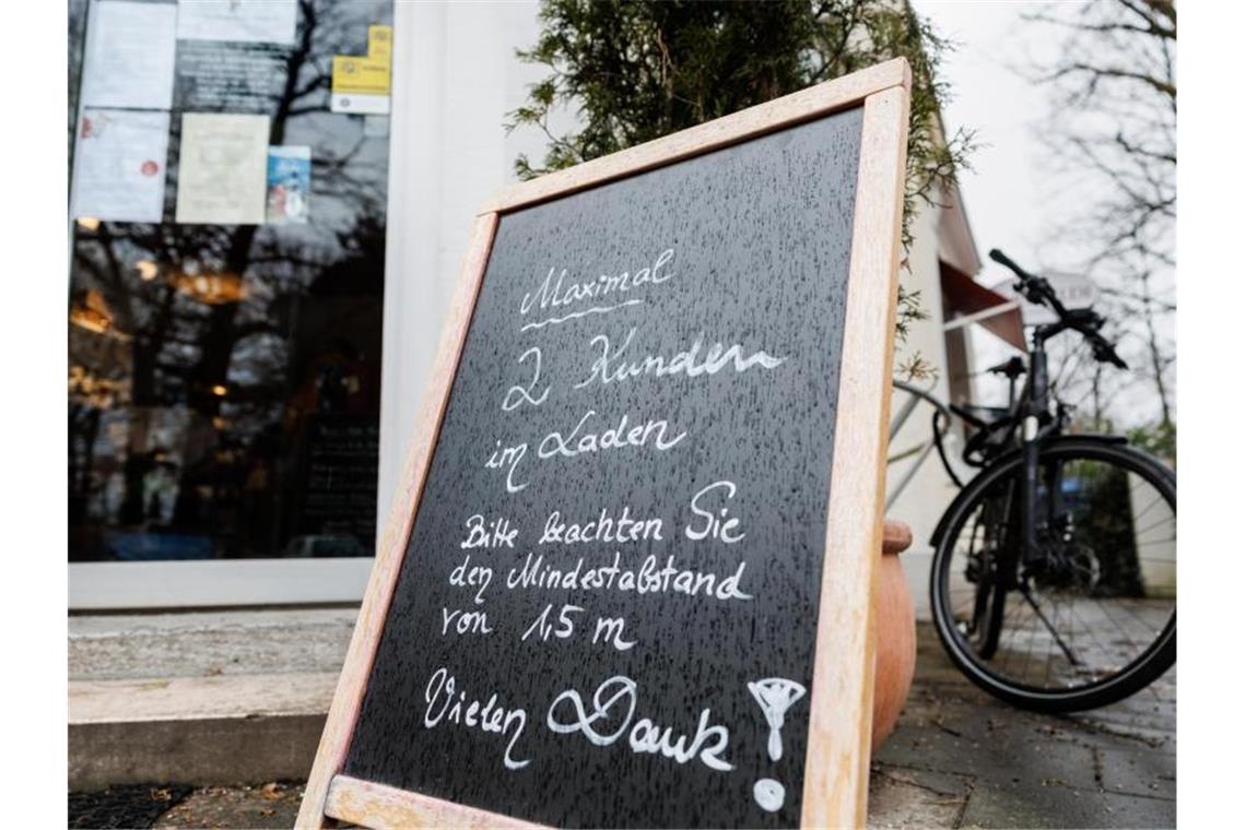 Streit über weiter nötige Corona-Absicherungen im Frühling Eine Tafel vor einem Münchener Geschäft weist auf die Maximalanzahl von 2 Personen im Laden hin. Foto: Matthias Balk/dpa
