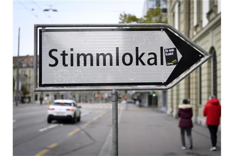 Eine Tafel weist auf ein Stimmlokal in Bern hin. Foto: Anthony Anex/KEYSTONE/dpa