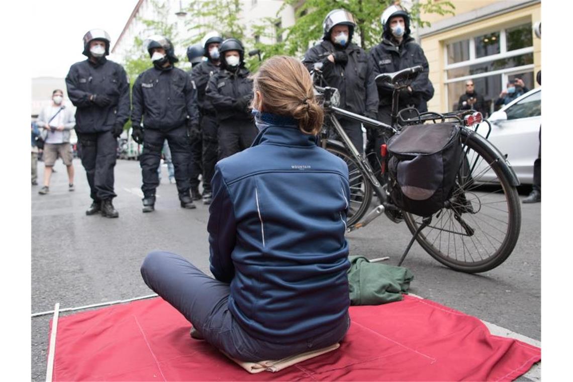Eine Teilnehmerin sitzt bei der Kundgebung in Berlin-Mitte auf einer mitgebrachten Decke. Foto: Jörg Carstensen/dpa
