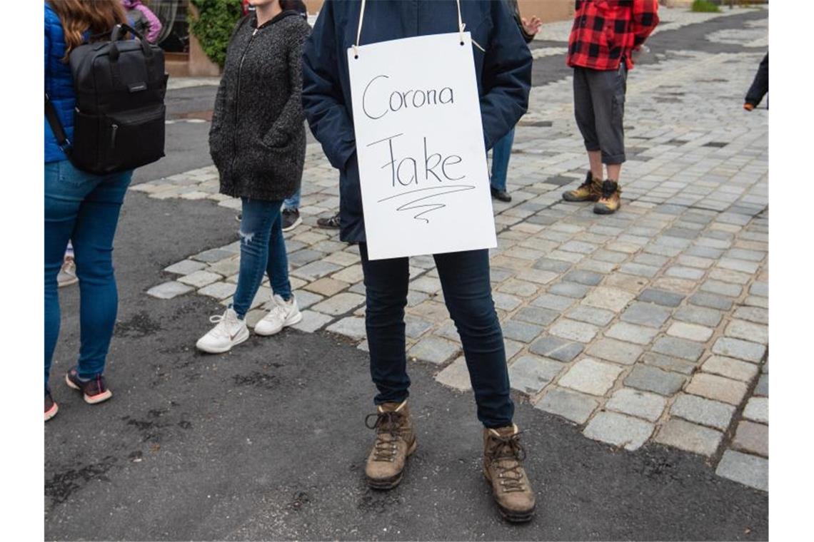 Eine Teilnehmerin trägt bei einer Demo gegen die Corona-Maßnahmen ein Schild mit der Aufschrift "Corona Fake". Foto: Nicolas Armer/dpa