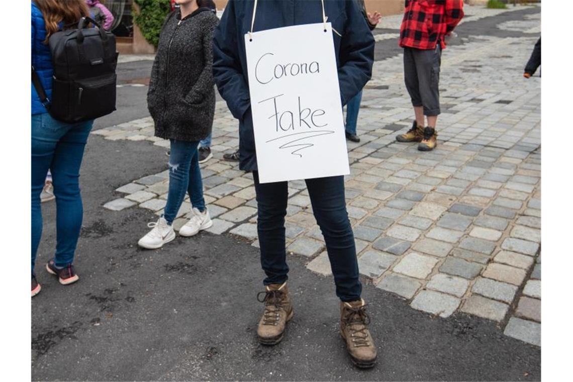 Warnung vor Verschwörungstheorien und Falschnachrichten Eine Teilnehmerin trägt bei einer Demo gegen die Corona-Maßnahmen ein Schild mit der Aufschrift "Corona Fake". Foto: Nicolas Armer/dpa