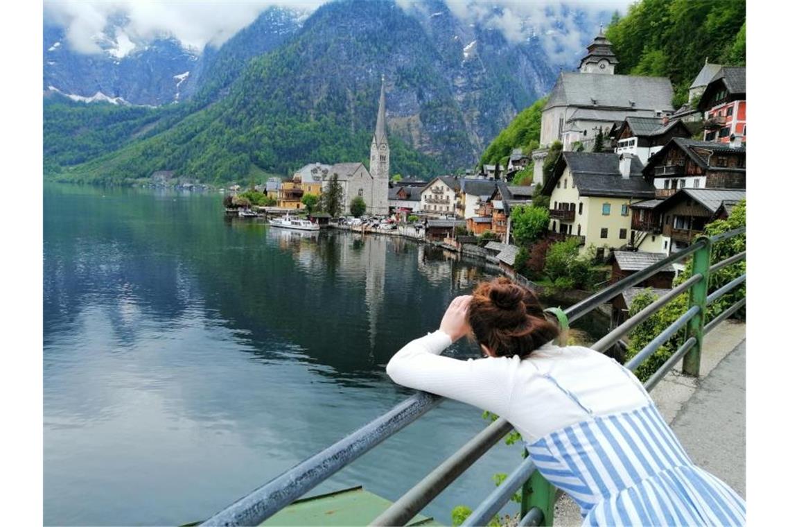 Eine Touristin fotografiert den Hallstätter See in Österreich. Hier scheint die Welt selbst im Corona-Sommer in der üblichen Ordnung zu sein. Foto: Matthias Röder/dpa