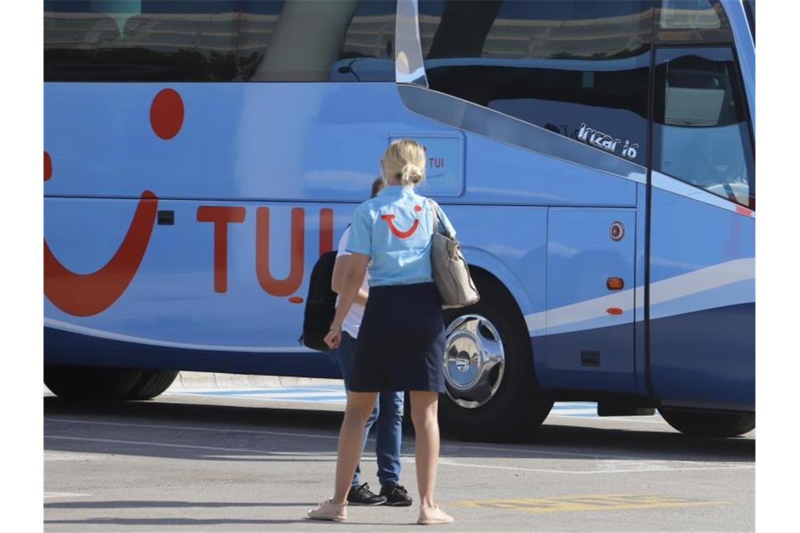 Eine TUI-Mitarbeiterin wartet am Flughafen Palma de Mallorca auf die ersten Reisenden. Foto: Clara Margais/dpa