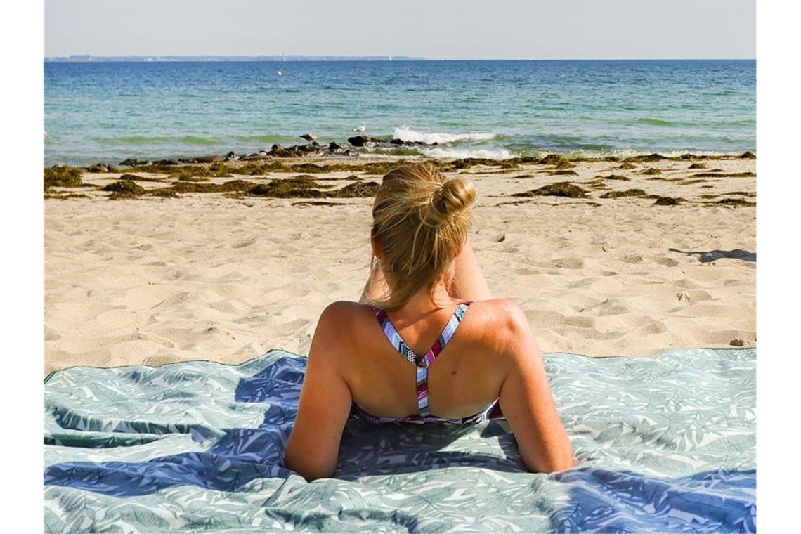 Eine Urlauberin genießt das sommerliche Wetter am Ostseeufer in Timmendorfer Strand. Foto: Ulrich Perrey/dpa