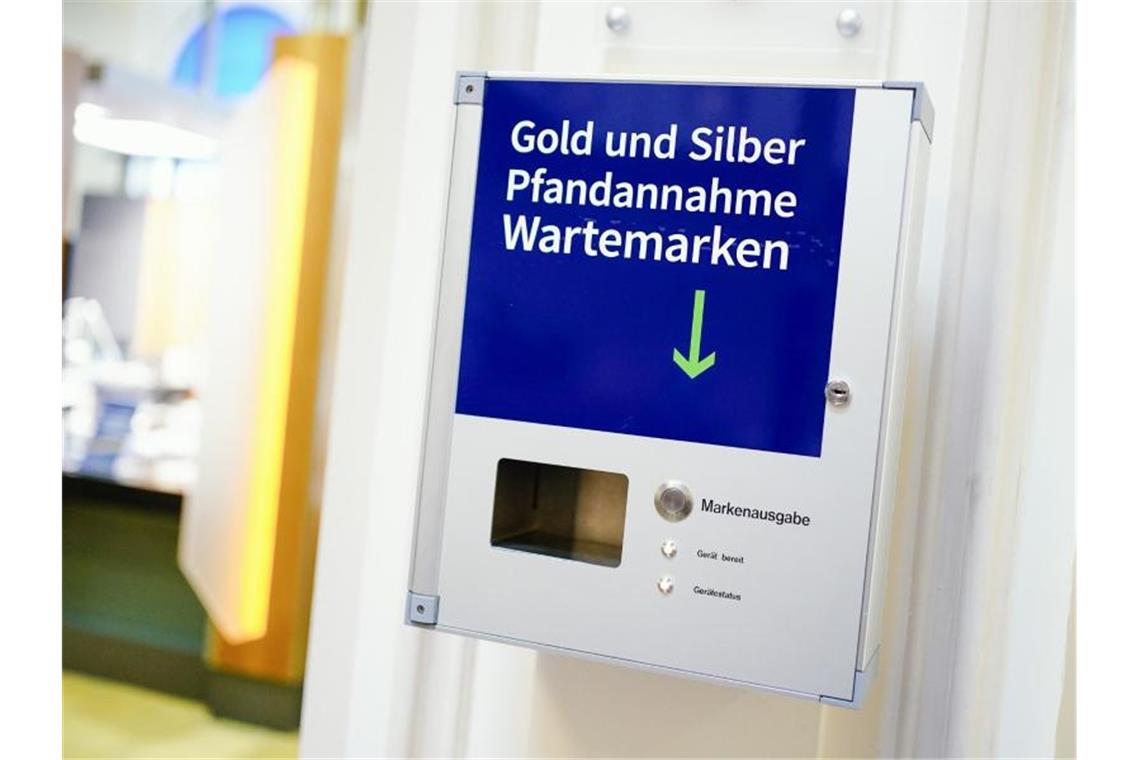 Eine Vorrichtung zur Ausgabe von Wartemarken mit der Aufschrift „Gold und Silber Pfandannahme Wartemarken“ hängt im Wartebereich des Leihamts. Foto: Uwe Anspach/dpa