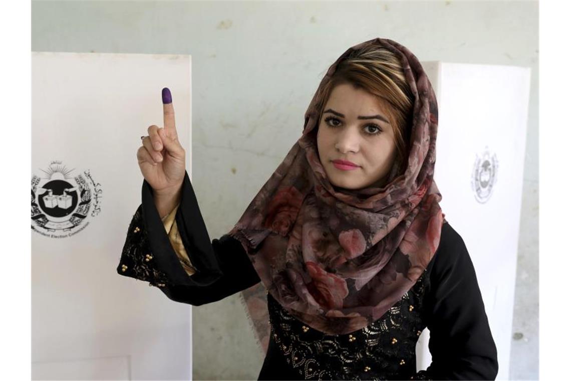 Eine Wählerin zeigt ihren mit Wahltinte markierten Zeigefinger vor einer Wahlkabine. Foto: Ebrahim Noroozi