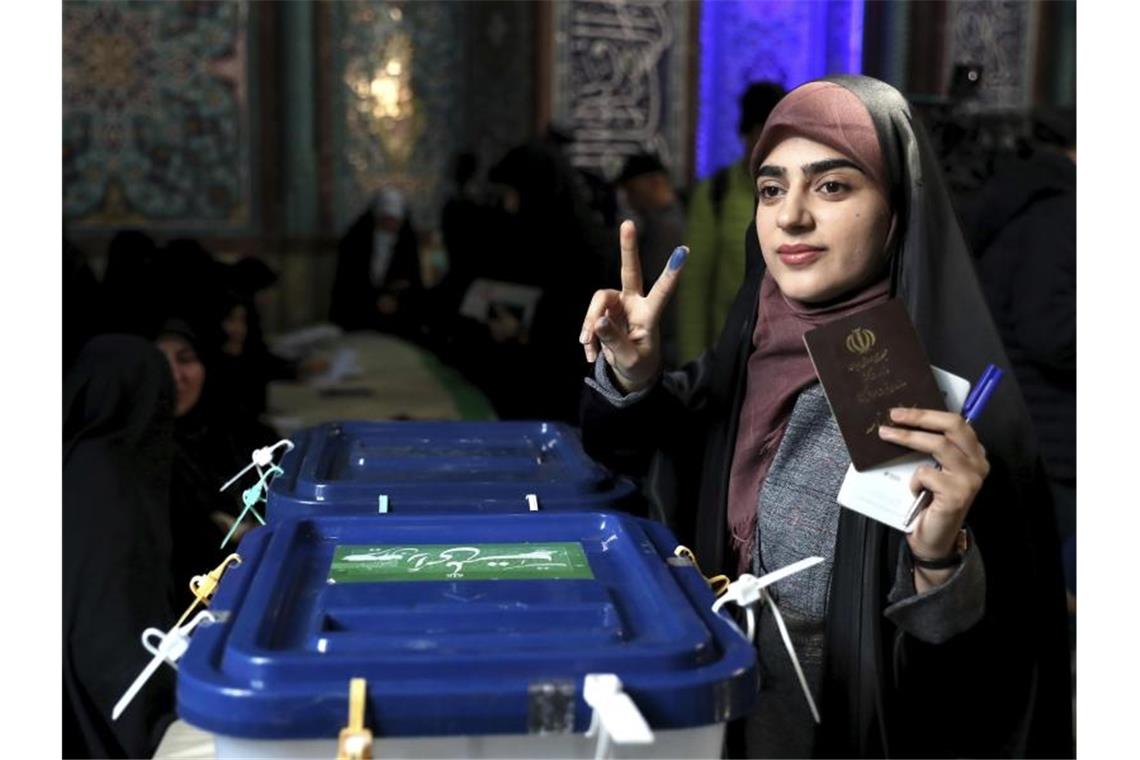 Eine Wählerin zeigt mit eingefärbten Fingern ein Siegeszeichen, während sie in Teheran ihre Stimme abgibt. Foto: Ebrahim Noroozi/AP/dpa