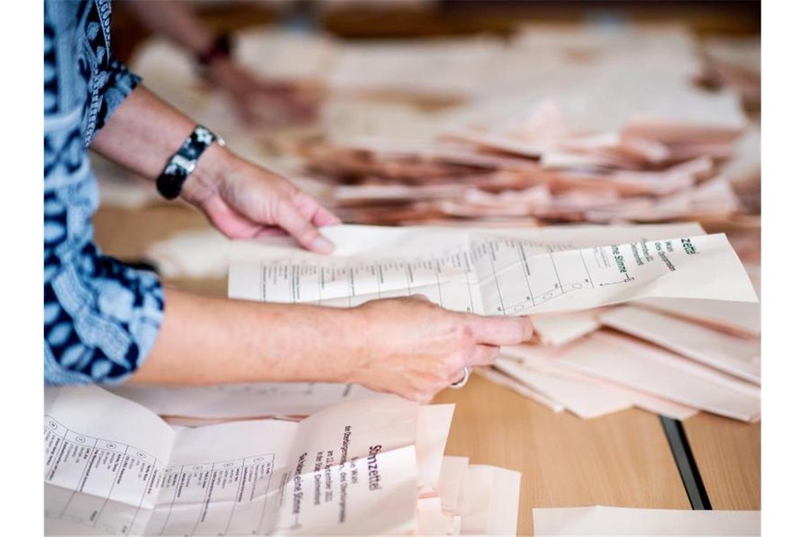 Eine Wahlhelferin sortiert in einer Grundschule die Stimmzettel für die Auszählung. Foto: Hauke-Christian Dittrich/dpa