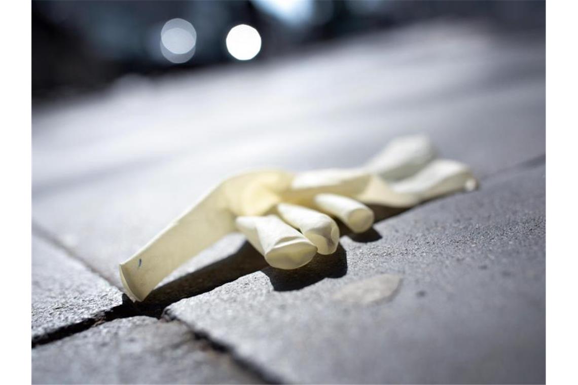 Eine weggeworfener Einweg-Schutzhandschuh auf einem Gehweg in Düsseldof. Foto: Martin Gerten/dpa