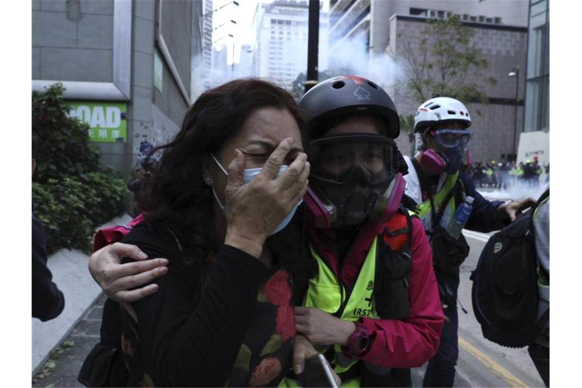 Eine weinende Demonstrantin wird an den Straßenrand geführt. Foto: Ng Han Guan/AP/dpa