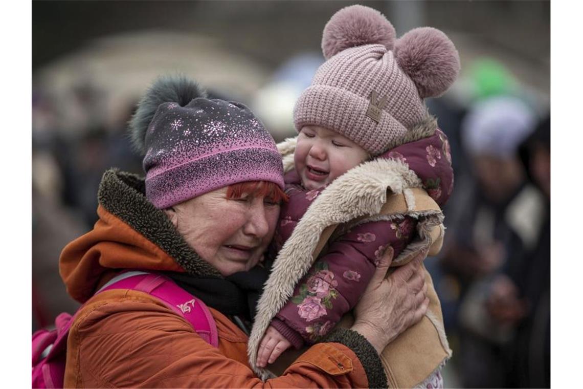 Eine weinende Frau mit einem Kind im Arm am Grenzübergang im polnischen Medyka. Foto: Visar Kryeziu/AP/dpa