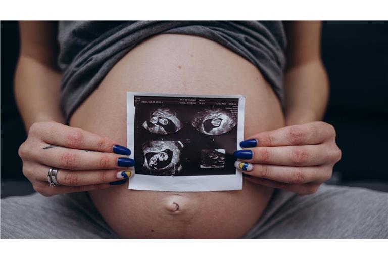 Eine werdende Mutter zeigt Ultraschallaufnahmen des heranwachsenden Babys in ihrem Mutterleib. (Symbolbild)