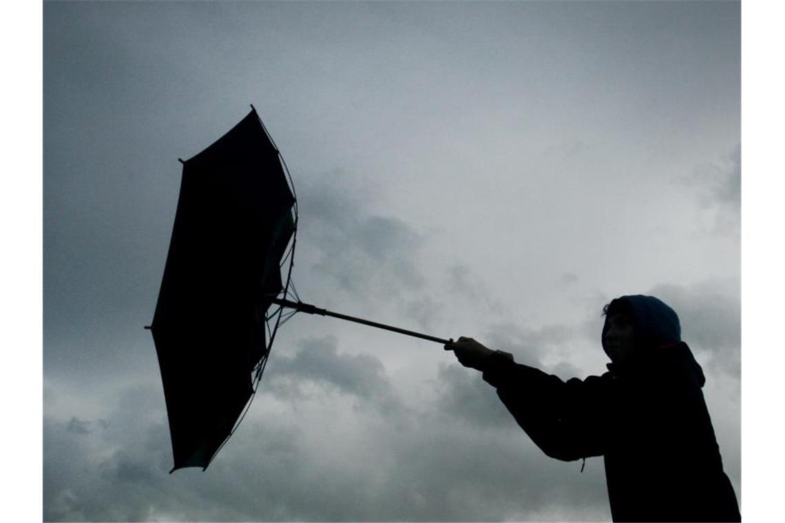 Eine Windböe erfasst den Regenschirm eines Spaziergängers. Foto: picture alliance / Karl-Josef Hildenbrand/dpa/Archivbild