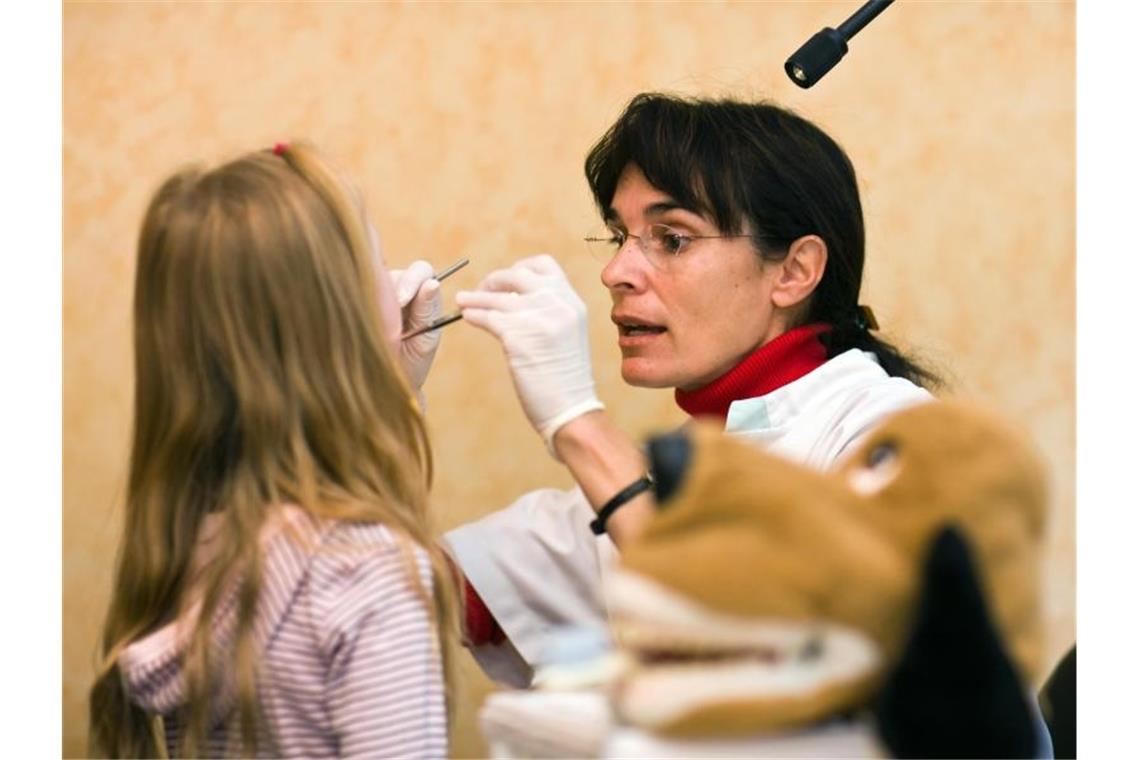 Eine Zahnärztin untersucht im Kindergarten die Zähne eines kleinen Mädchens. Foto: Patrick Pleul/Archivbild