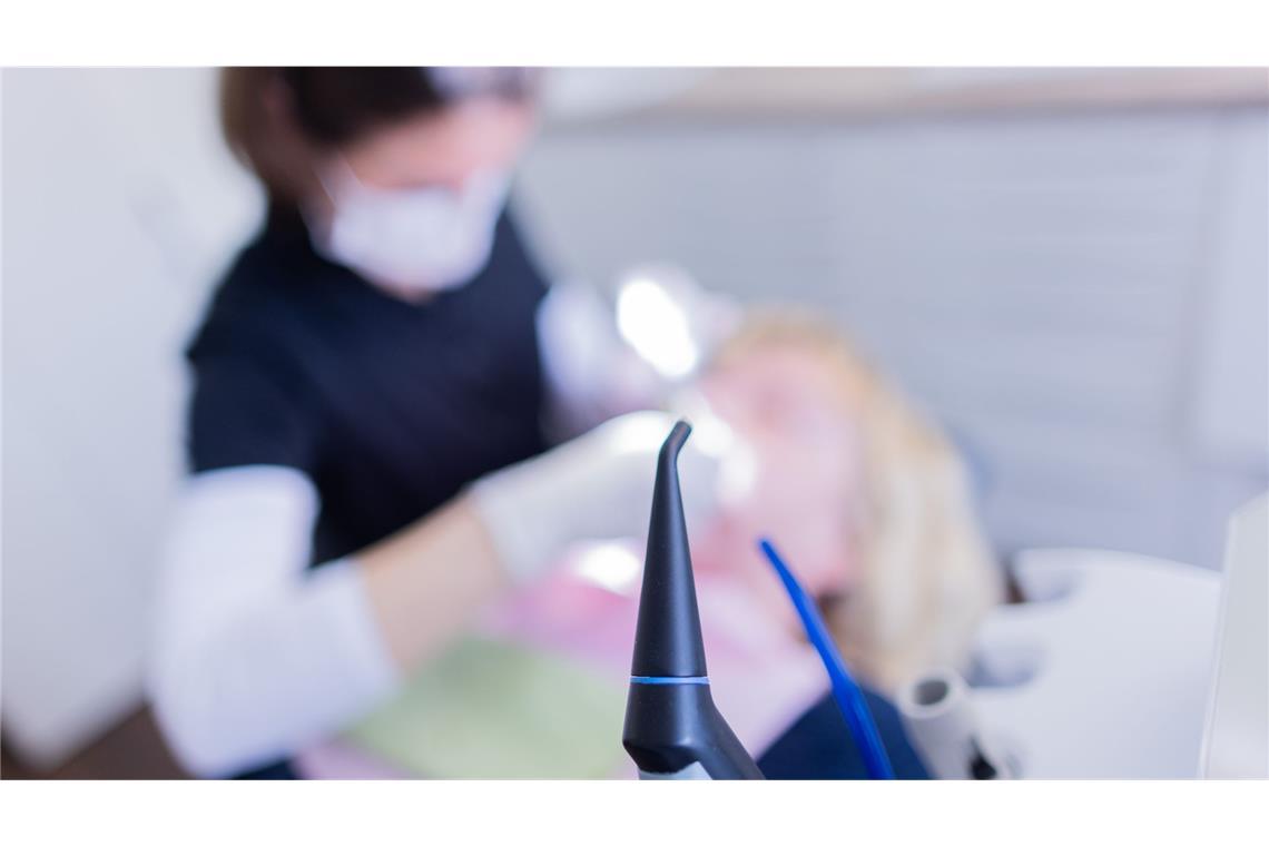 Eine Zahnarzthelferin führt an einer Patientin eine Zahnreinigung durch.