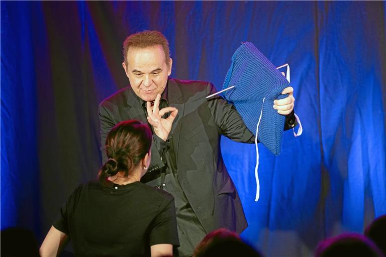 Eine Zuschauerin unterstützt den Magier beim Trick. Sie soll die große Stricknadel durch das blaue Kissen ziehen. Darin befindet sich ein Spiegel – oder nicht? Foto: Alexander Becher