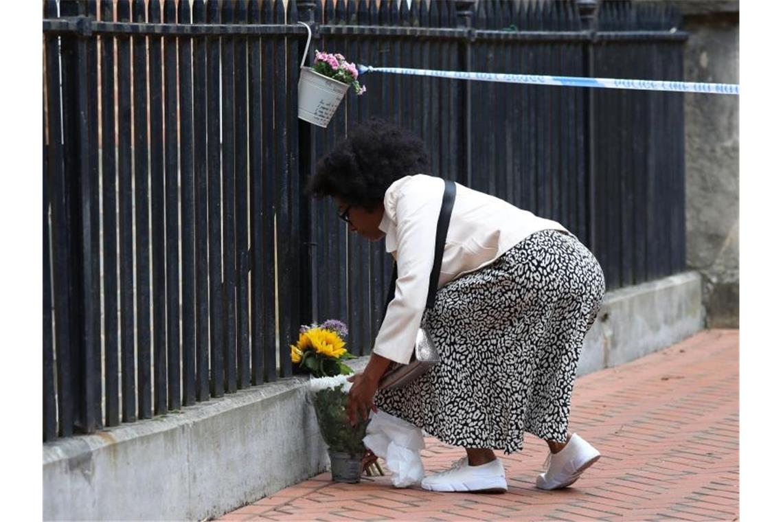 Eine Frau legt zum Gedenken an die Opfer im Stadtzentrum von Reading Blumen nieder. Foto: Jonathan Brady/PA Wire/dpa