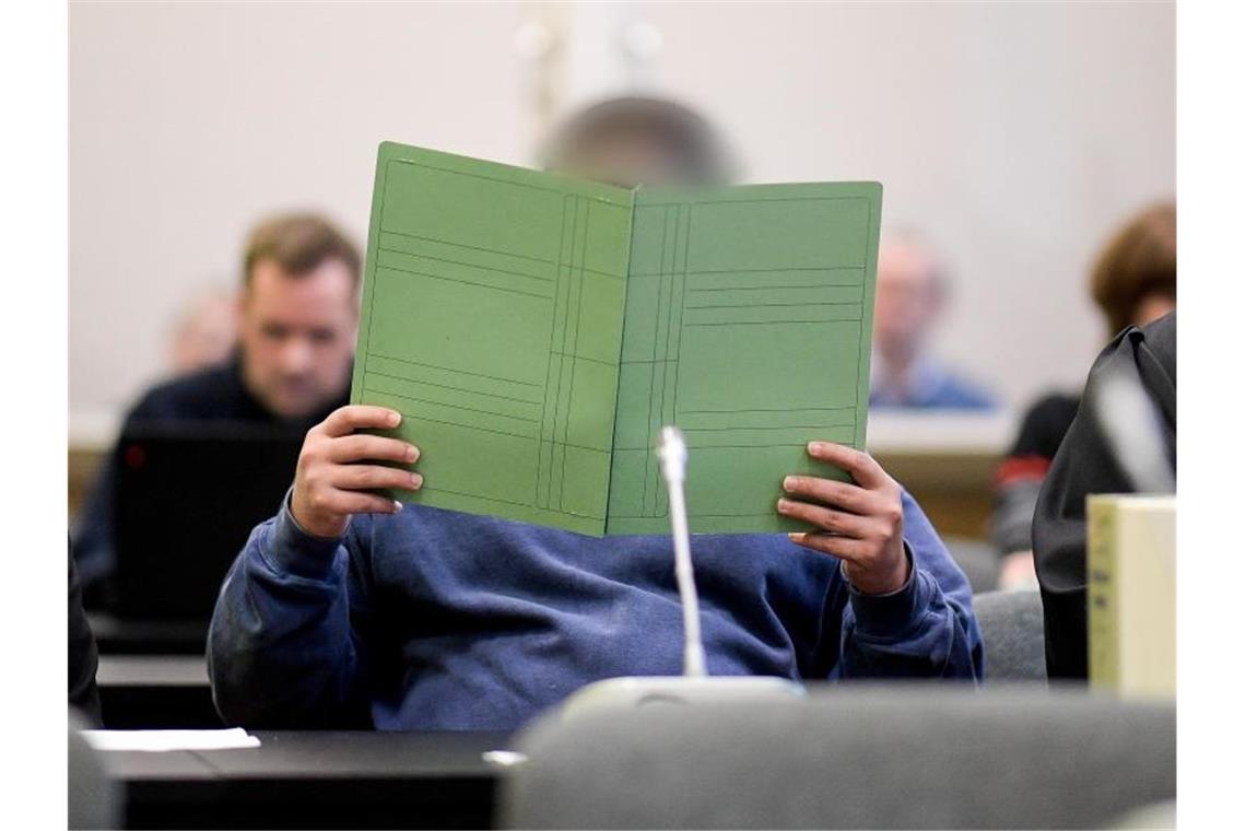 10.000 Euro für Schüsse auf Rockerboss - Geständnis erwartet Einer der Angeklagten verdeckt sein Gesicht mit einem Aktenordner. Foto: Axel Heimken/dpa