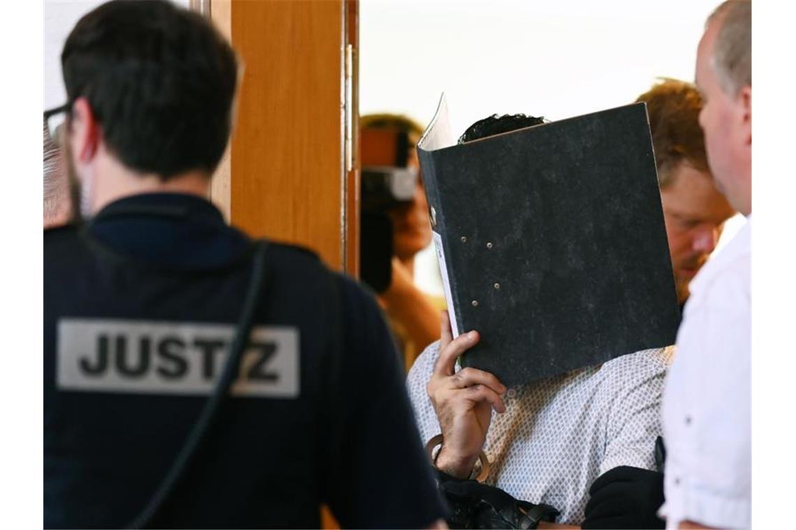 Nach Gruppenvergewaltigung weisen Türsteher Vorwürfe zurück Einer von elf Angeklagten wird vor dem Prozessbeginn von einem Justizbeamten in einen Gerichtssaal im Landgericht gebracht. Foto: Patrick Seeger/dpa/Archivbild