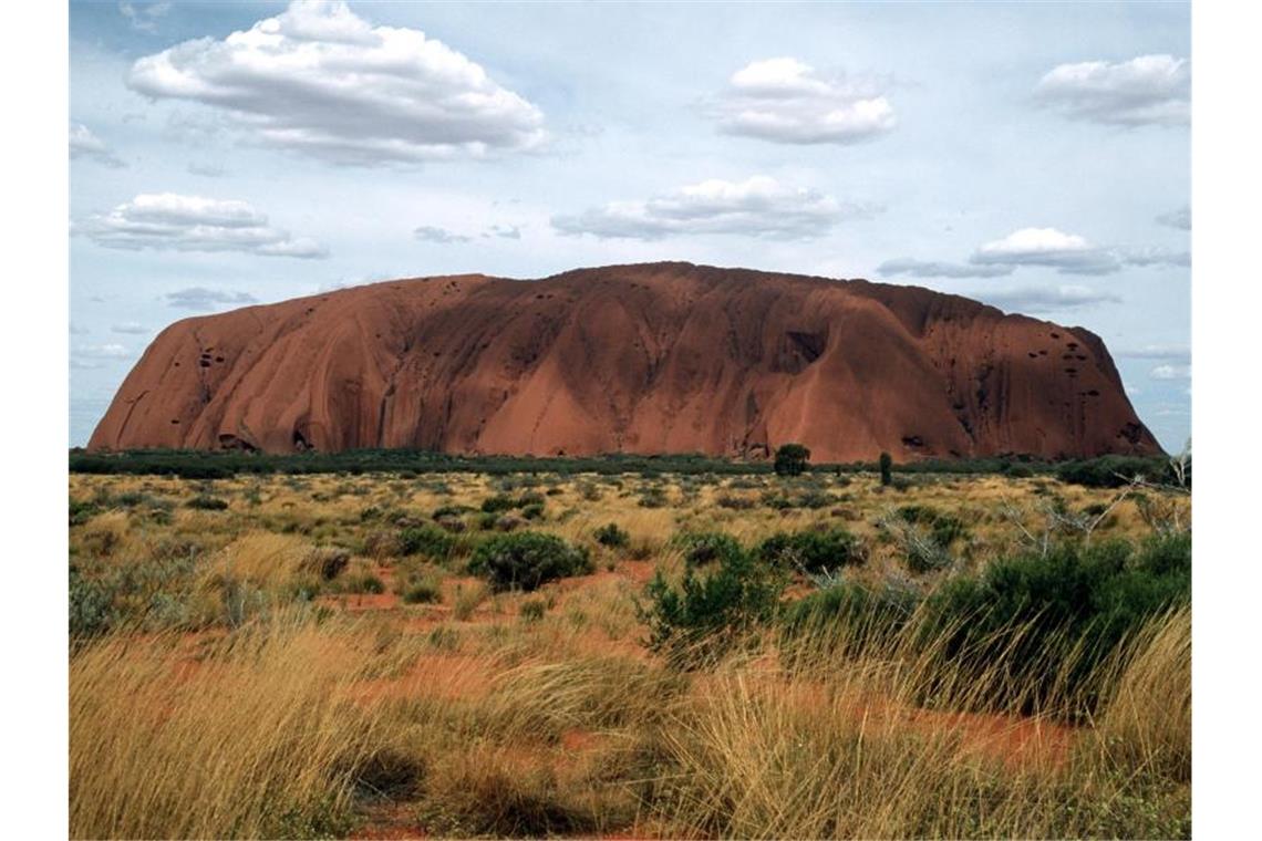 Eines der bekanntesten Wahrzeichen Australiens, der riesige Sandstein Uluru oder Ayers Rock ist in der zentralaustralischen Wüste zu sehen. Foto: picture alliance / dpa