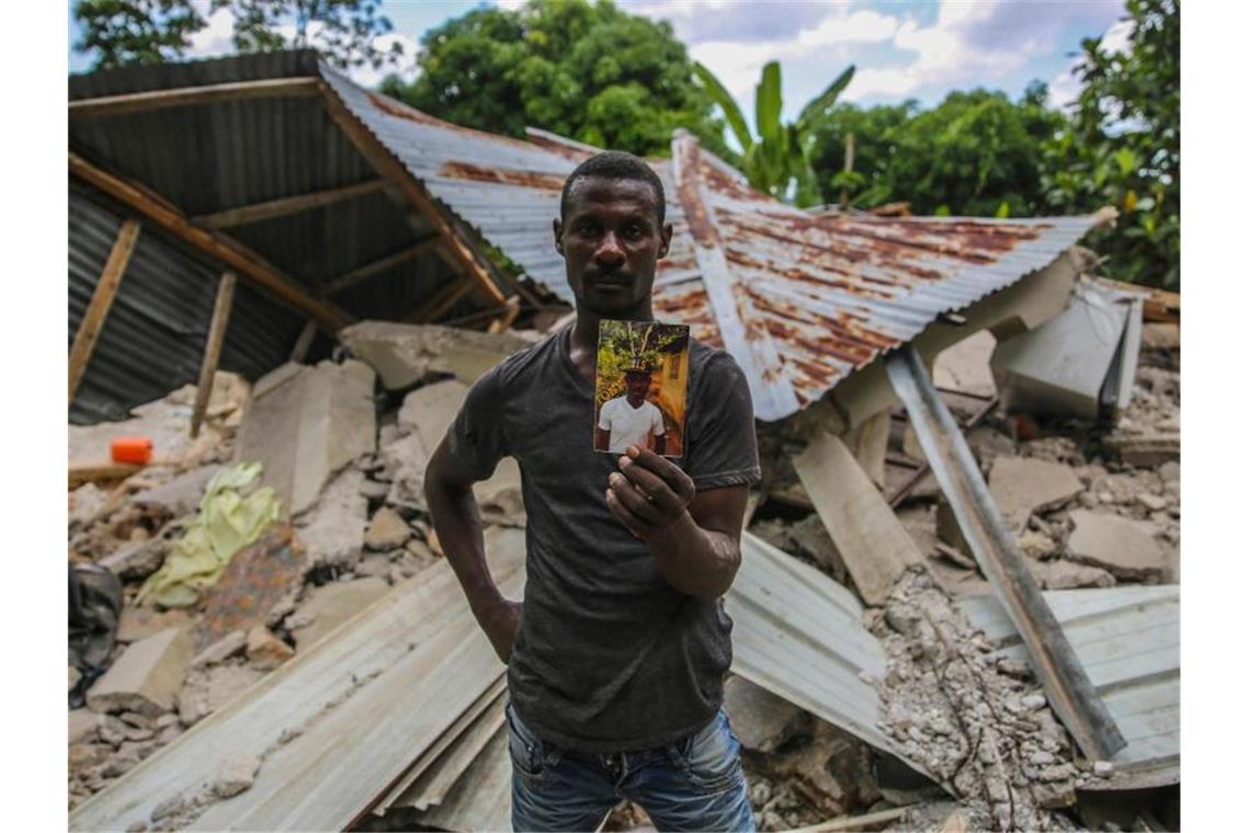 Zahl der Toten nach Haiti-Beben steigt auf 1297 Ein Haitianer mit einem Foto seines bei dem Erdbeben ums Leben gekommenen Bruders. Foto: Joseph Odelyn/AP/dpa