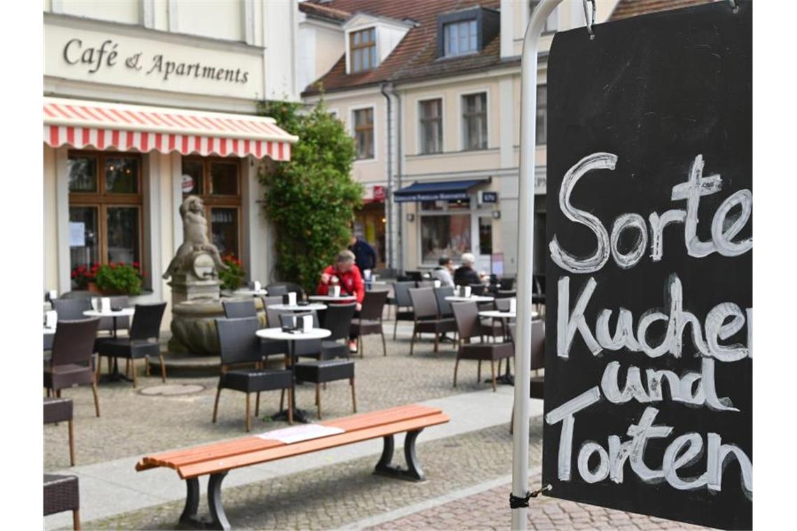 Einige Gäste sitzen in einem Café an der Straße. Foto: Bernd Settnik/dpa-Zentralbild/dpa/Symbolbild