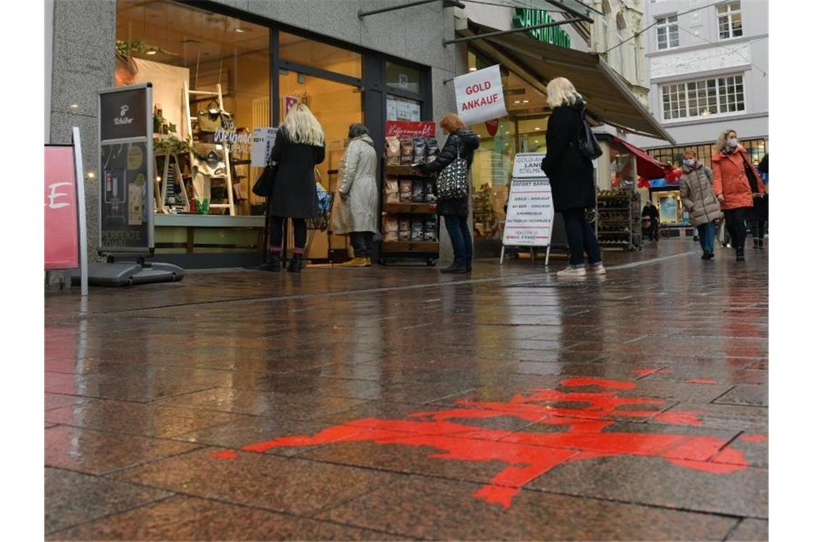 Einkaufen mit Hindernissen: Vor einem Bekleidungsgeschäft in der Bremer Innenstadt warten Kunden in einer Schlange. Foto: Michael Bahlo/dpa