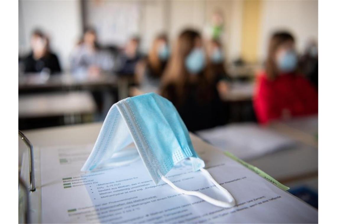 Ein Mund-Nasen-Schutz liegt im Unterricht auf Unterlagen. Foto: Matthias Balk/dpa/Symbolbild