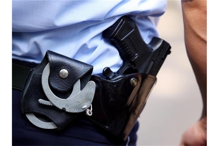 Ein Polizist trägt Handschellen und seine Dienstwaffe bei sich. Foto: Oliver Berg/dpa/Symbolbild