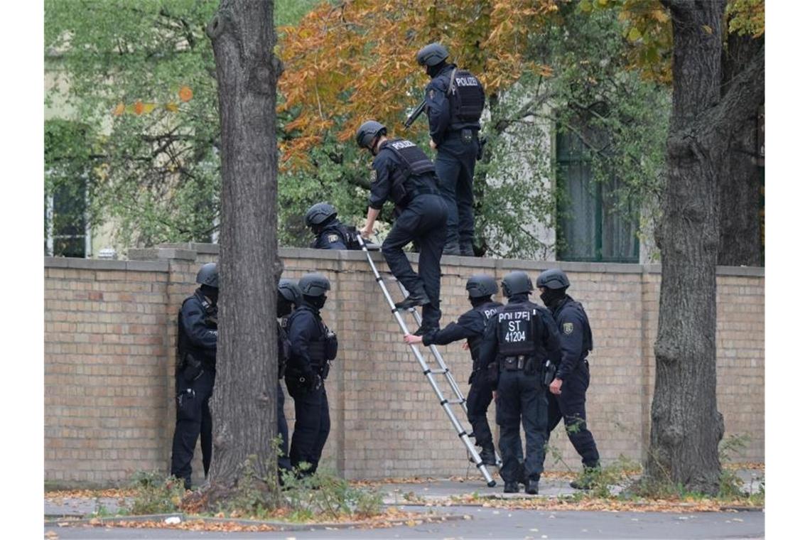 Einsatz in Halle: Polizisten mit Schutzhelmen übersteigen eine Mauer. Foto: Sebastian Willnow/dpa-Zentralbild/dpa