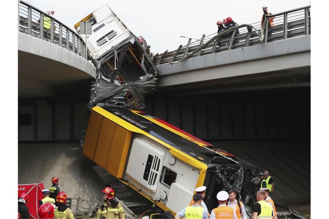 Einsatzkräfte arbeiten an der Unfallstelle. Mindestens ein Mensch ist bei dem Absturz des Linienbusses ums Leben gekommen. Foto: Czarek Sokolowski/AP/dpa