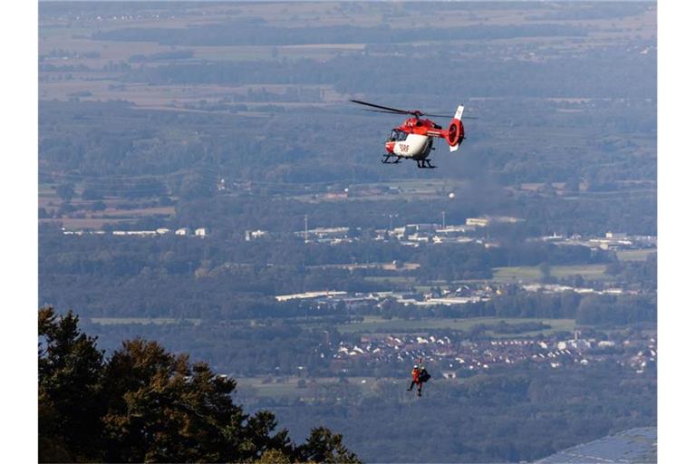 Einsatzkräfte der DRF Luftrettung sowie der Bergwacht hängen von einem Rettungshubschrauber am Seil. Foto: Philipp von Ditfurth/dpa