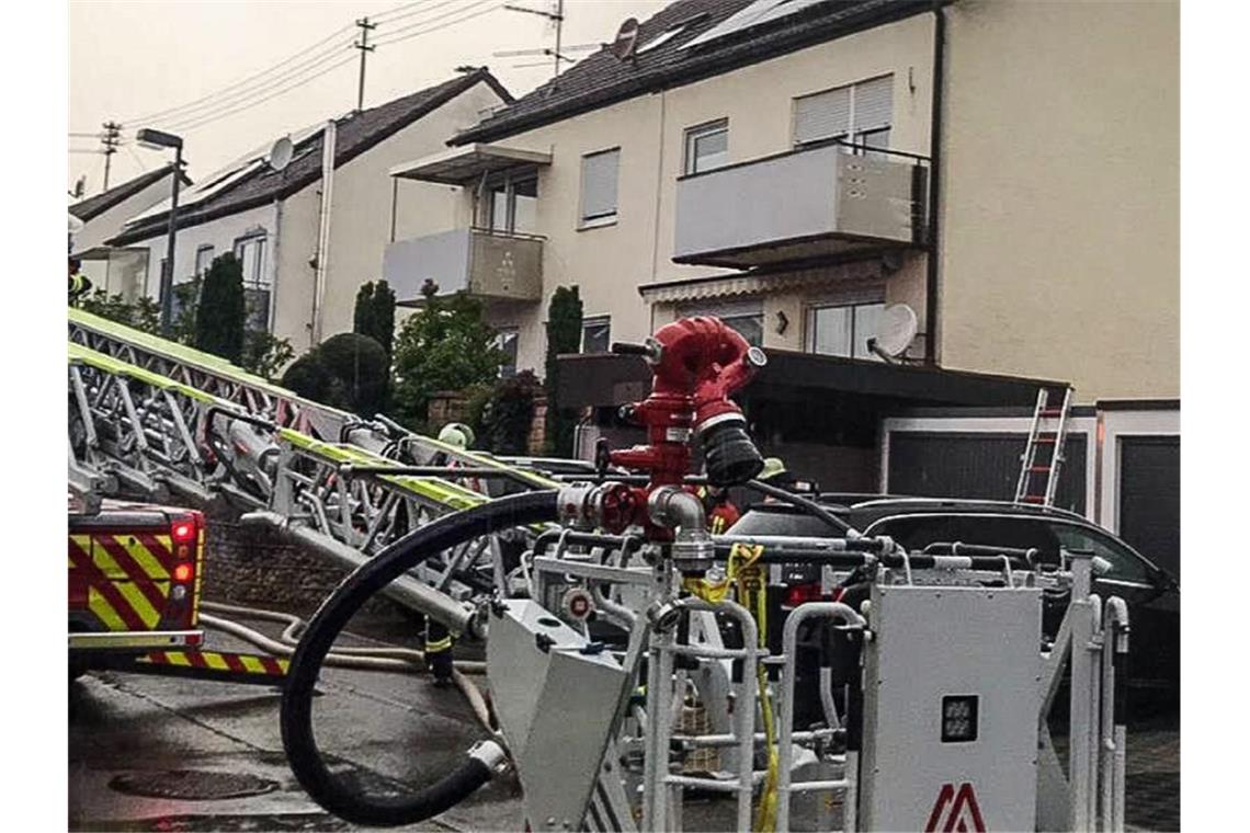 Einsatzkräfte der Feuerwehr bei Löscharbeiten an einem Wohnhaus im baden-württembergischen Herrenberg. Heftige Unwetter haben auch am Dienstag etliche Regionen in Deutschland getroffen. Vor allem aus einigen Gebieten im Süden wurden am Abend Gewitter mit Starkregen gemeldet. Foto: Dettenmeyer/SDMG/dpa