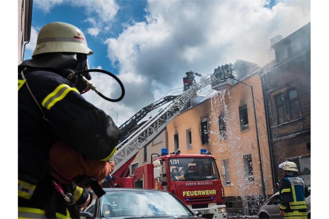 Einsatzkräfte der Feuerwehr löschen den Brand in dem Mehrfamilienhaus in Neunkirchen. Foto: Oliver Dietze