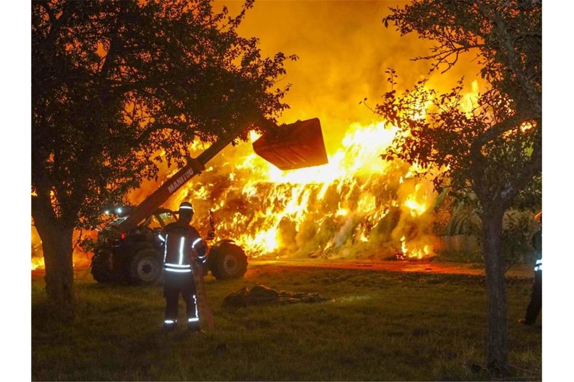 Einsatzkräfte der Feuerwehr löschen einen Brand von rund 400 Strohballen. Foto: Franziska Hessenauer/dpa/Archivbild