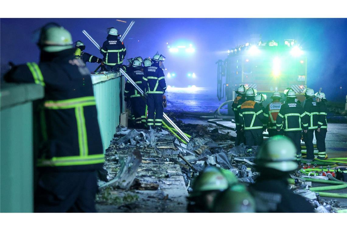 Einsatzkräfte der Feuerwehr sind dabei einen Brand in einem Industriegebiet im Hamburger Hafen zu löschen.