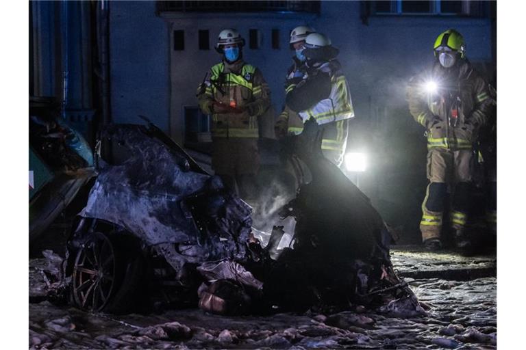 Einsatzkräfte der Feuerwehr stehen am Treptower Park neben dem Autowrack. Foto: Paul Zinken/dpa