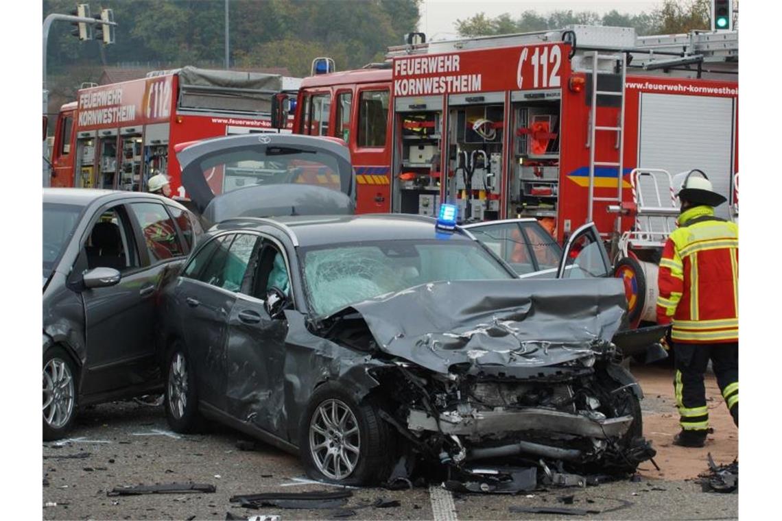 Schwerer Unfall mit Polizeiauto: fünf Verletzte Einsatzkräfte der Feuerwehr stehen an einer Unfallstelle neben einem Zivil-Fahrzeug der Polizei. Foto: Andreas Rosar/dpa