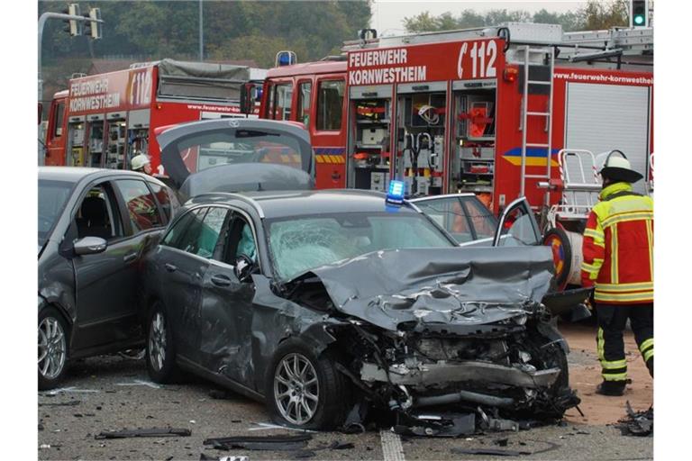 Einsatzkräfte der Feuerwehr stehen an einer Unfallstelle neben einem Zivil-Fahrzeug der Polizei. Foto: Andreas Rosar/dpa