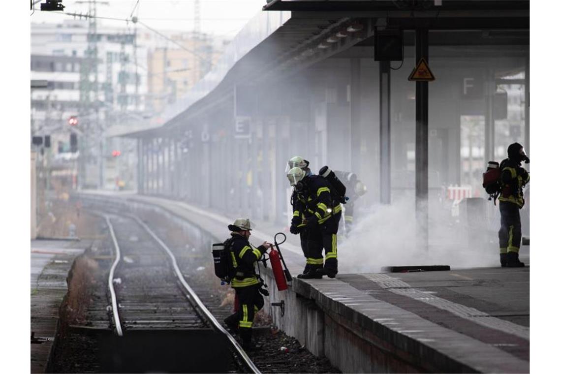 Einsatzkräfte der Feuerwehr stehen während eines Löscheinsatzes auf einem Gleis und Gleisbett des Hauptbahnhofs. Foto: Marijan Murat/dpa
