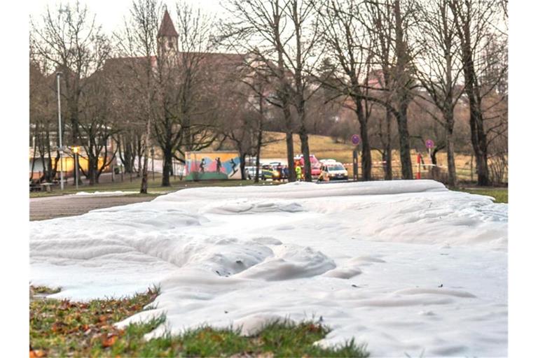 Einsatzkräfte der Feuerwehr und der Polizei sperren eine Parkfläche ab, an der sich ein Schaumteppich gebildet hatte. Foto: Jason Tschepljakow/dpa