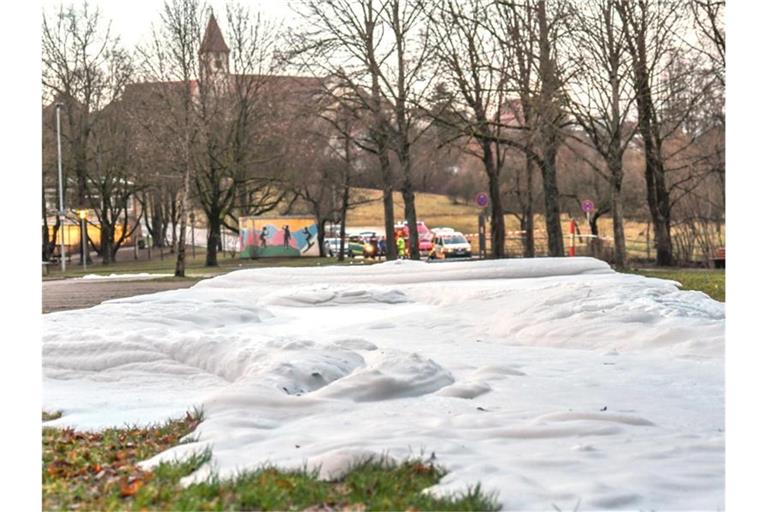Einsatzkräfte der Feuerwehr und der Polizei sperren eine Parkfläche ab, an der sich ein Schaumteppich gebildet hatte. Foto: Jason Tschepljakow/dpa/Archivbild