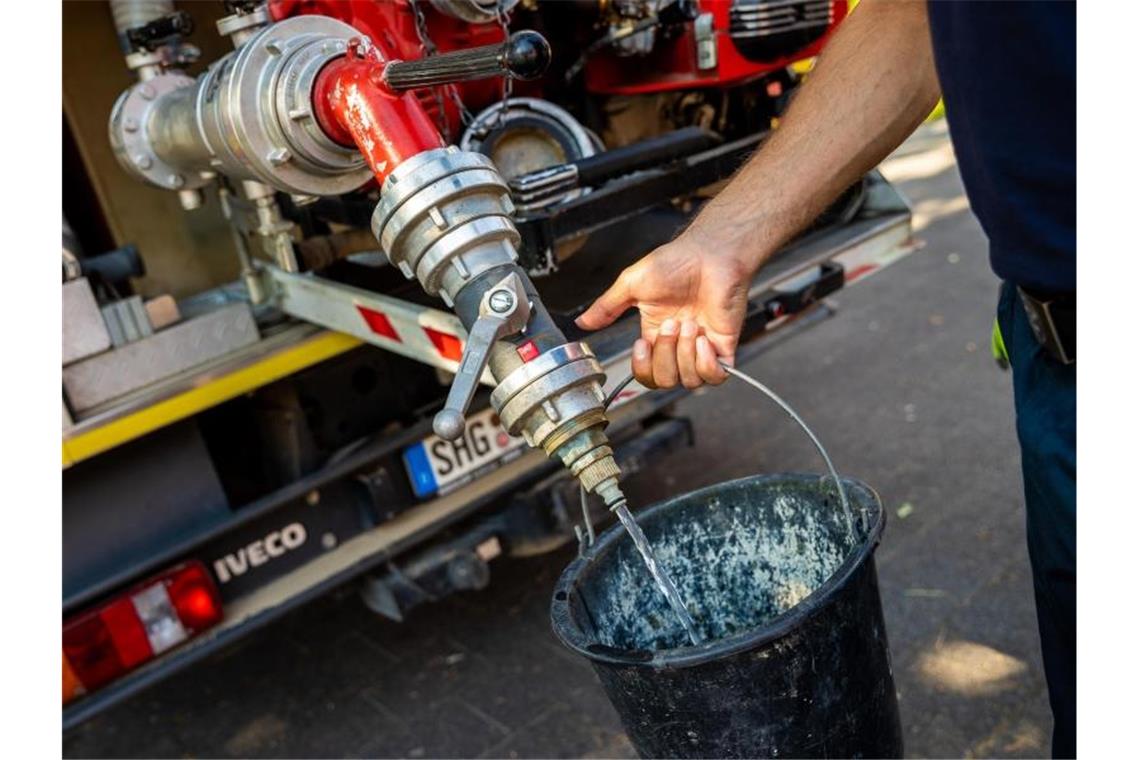 Einsatzkräfte der Freiwilligen Feuerwehr Lauenau zapfen Löschwasser aus dem Tank eines ihrer Einsatzfahrzeuge. Foto: Moritz Frankenberg/dpa