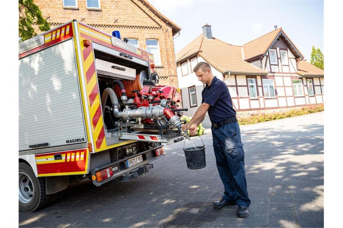 Lauenau geht das Trinkwasser aus: Lage wieder „beherrschbar“ Einsatzkräfte der Freiwilligen Feuerwehr zapfen Löschwasser aus dem Tank eines ihrer Einsatzfahrzeuge. Foto: Moritz Frankenberg/dpa