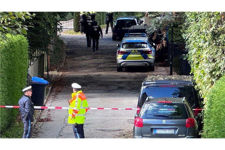 Einsatzkräfte der Polizei stehen bei einer Durchsuchung in einer Straße. Die Polizei geht bei einem Großbrand mit Explosionen im Münchner Norden derzeit von einem privaten Hintergrund aus.