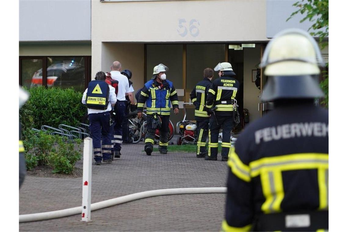 Einsatzkräfte der Polizei und Feuerwehr bei dem Großeinsatz vor dem Mehrfamilienhaus in Achern. Foto: Benedikt Spether/dpa