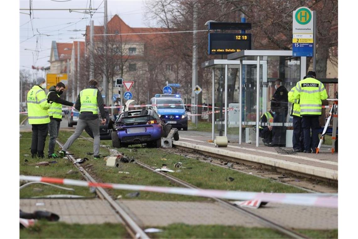 Einsatzkräfte der Polizei und Sachverständige sind an der Unfallstelle neben dem Unfallwagen im Gleisbett der Straßenbahn im Einsatz. Foto: Jan Woitas/dpa