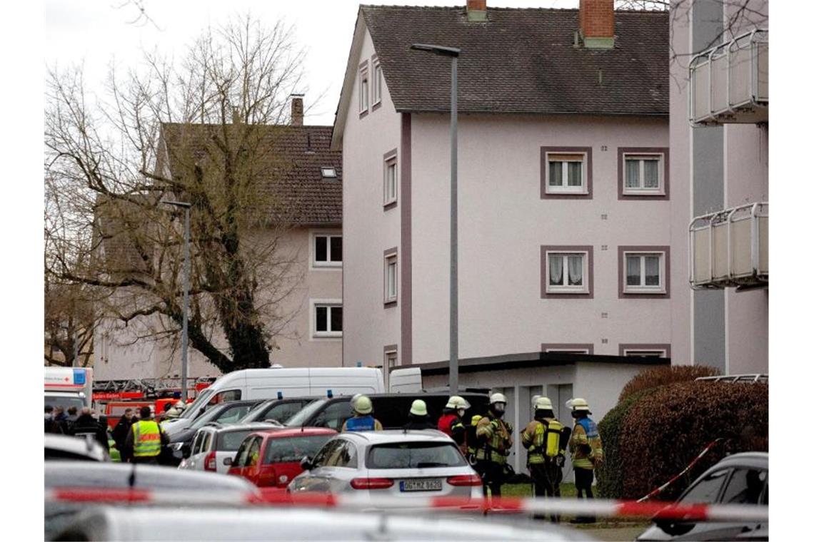 Einsatzkräfte von Polizei und Feuerwehr stehen bei einem Großeinsatz in Baden-Baden vor einem Mehrfamilienhaus. Foto: Philipp von Ditfurth/dpa