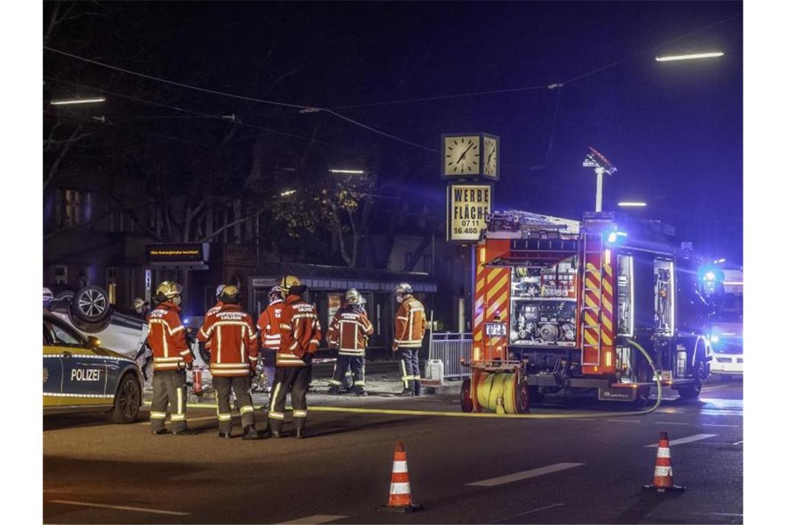 Einsatzkräfte von Polizei und Feuerwehr stehen in Karlsruhe neben einem auf dem Dach liegenden Fluchtfahrzeug. Foto: Aaron Klewer/Einsatz-Report24 /dpa